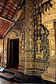 Wat Xieng Thong temple in Luang Prabang, Laos. The facade of the sim decorated with gold stencilling on a black lacquer background. 